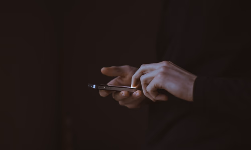 A person looking at a smartphone in a dark room, representing the struggle with digital addiction and the need for private recovery tools.