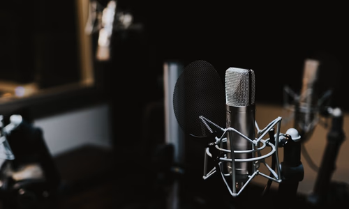 A close-up studio microphone in a dimly lit broadcast setup, representing the merger of AI power and media influence.