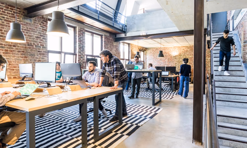 A modern office with human employees and symbolic AI agents working together representing McKinsey's hybrid workforce