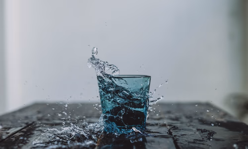 A clean, minimalist glass of water on a dark background, representing the purity and privacy of Aura Water's design.