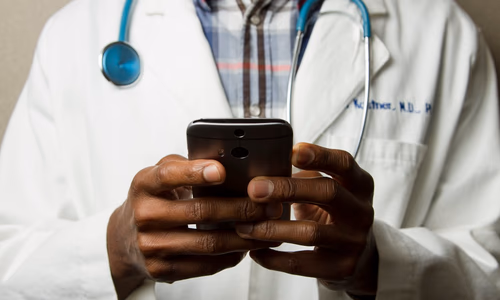 A person's hand holding a smartphone displaying a health-related AI interface, with a stethoscope in the background, representing the intersection of digital wellness and medical technology.