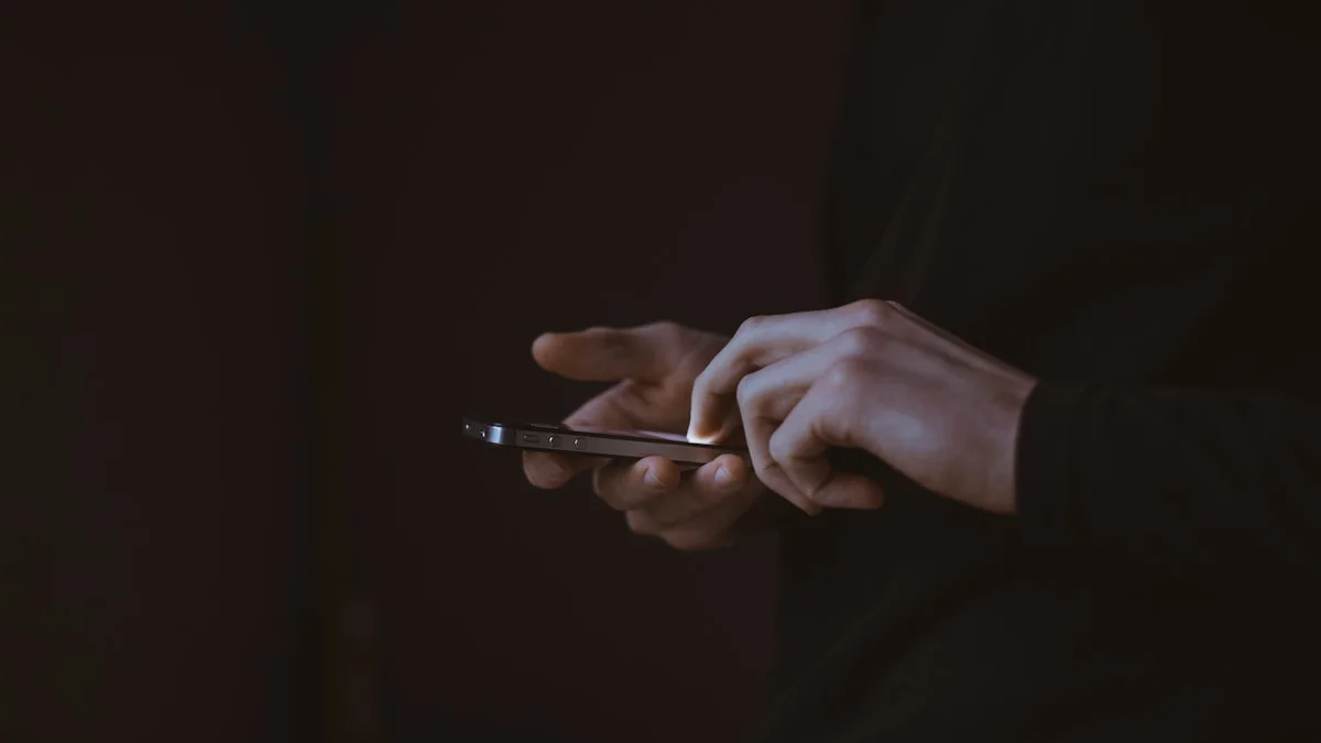 A person looking at a smartphone in a dark room, representing the struggle with digital addiction and the need for private recovery tools.