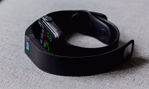 Smartwatch and smartphone showing wellness data while a Google Health interface overlays the screen, representing Fitbit rebrand