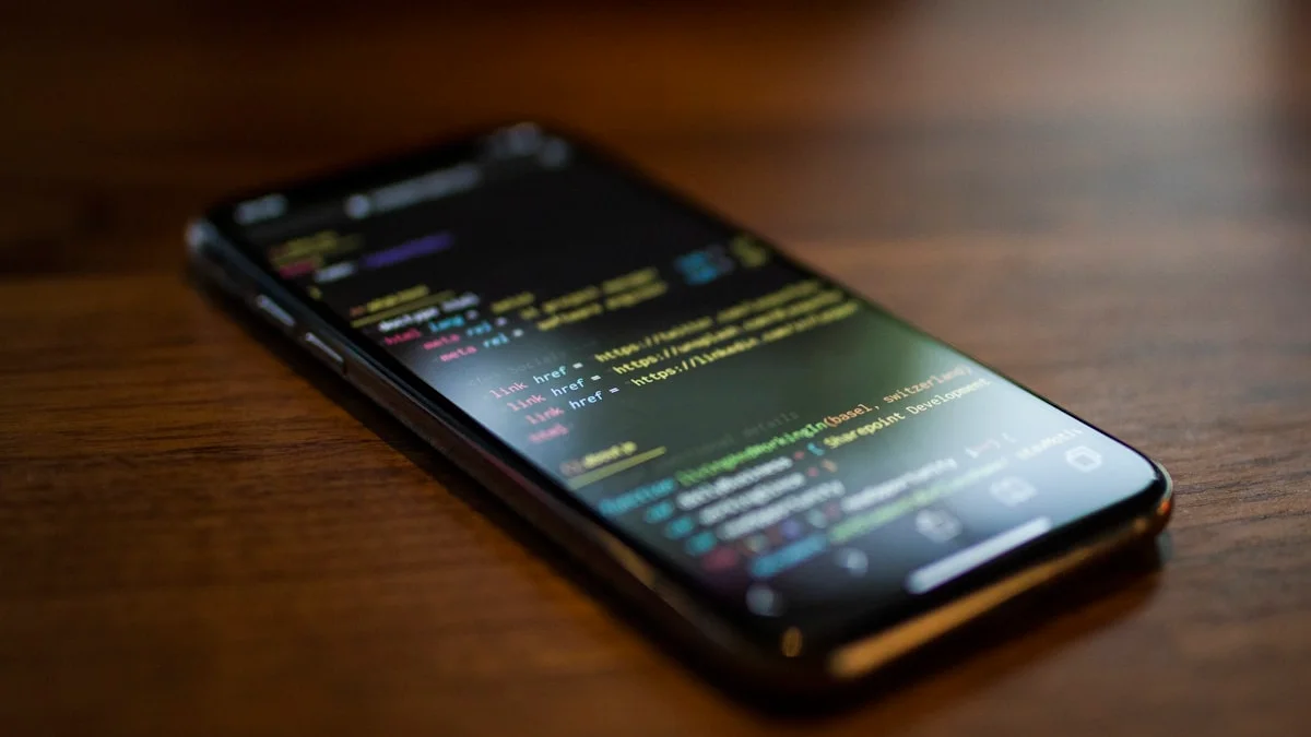 Developer using a phone to monitor a coding agent running on a laptop