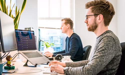 Office employees on computers representing Meta's Claudeonomics internal AI token usage leaderboard competition in 2026